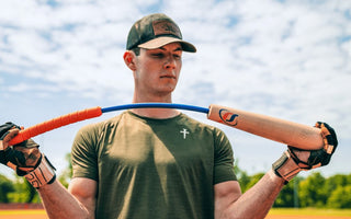 A man in a green T-shirt and baseball hat bends the Perfect Swings USA lag bat outside on a sunny day.