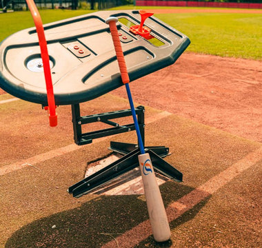 A close-up of the Perfect Swings USA Lag Bat propped up against the Swing Path Trainer IV on a baseball home plate.